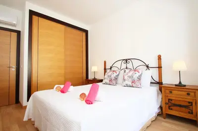 a bedroom with a white bed with pink pillows at Apartment Caracas 2 by Algarve Vacation in Albufeira