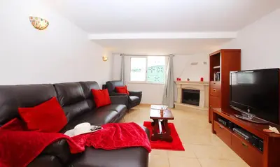 a living room with a black leather couch and a flat screen tv at Villa Saint Martin by Algarve Vacation in Albufeira