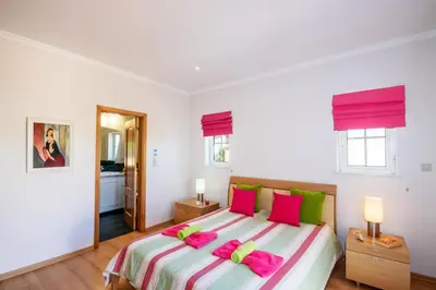 a bedroom with a large bed with pink and green pillows at Villa Savannah by Algarve Vacation in Almancil