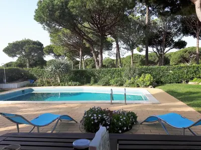 a swimming pool in a yard with chairs and trees at Alsouk in Vilamoura