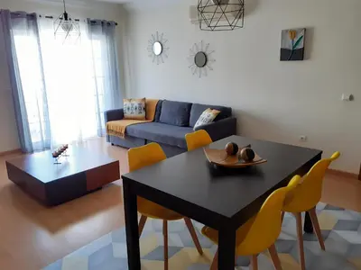 a living room with a black table and yellow chairs at Apartamento Alfarrobeira Mar in Quarteira