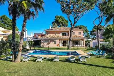 a house with a swimming pool and palm trees at Villa with Garden and Pool in Vilamoura