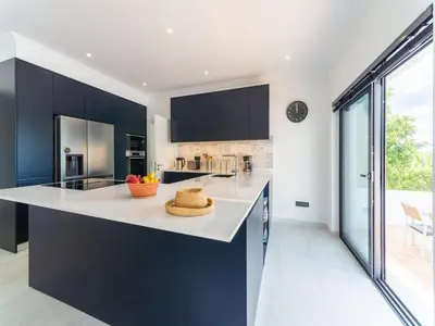 a kitchen with white countertops and blue cabinets at Casa O Sonho near Faro with private pool in Santa Bárbara de Nexe