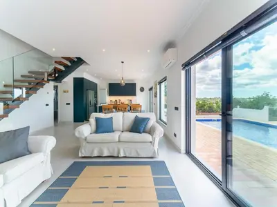 a living room with two white couches and a pool at Casa O Sonho near Faro with private pool in Santa Bárbara de Nexe