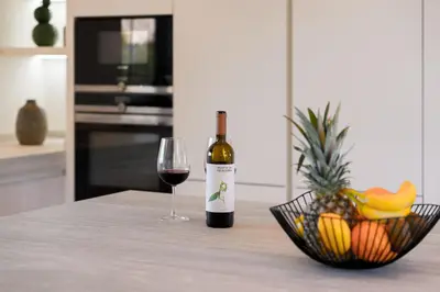 a bottle of wine and a bowl of fruit on a table at Villa Coral - Varandas do Lago in Almancil
