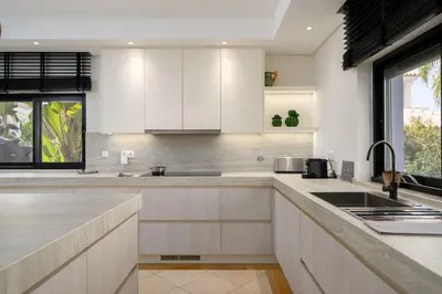 a kitchen with white cabinets and a sink at Villa Coral - Varandas do Lago in Almancil