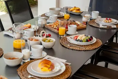 a table with plates of breakfast foods and orange juice at Villa Coral - Varandas do Lago in Almancil