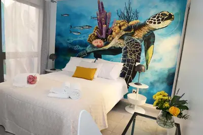 a bedroom with a bed with a painting of a sea turtle at Le Jardin Secret de Faro Guesthouse in Faro