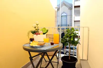 a table with a plate of food on a balcony at Le Jardin Secret de Faro Guesthouse in Faro
