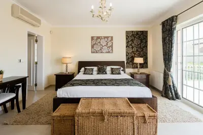 a bedroom with a bed and a desk and windows at Casa Lago in Quinta do Lago