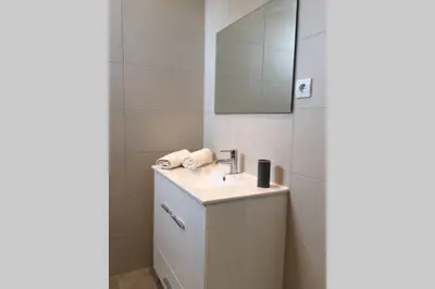 a white bathroom with a sink and a mirror at Edifico Ouramar T2 in Albufeira