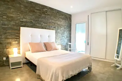 a bedroom with a large bed and a brick wall at Edifico Ouramar T2 in Albufeira