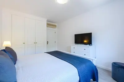 a white bedroom with a bed and a television at Amazing apartment in Albufeira in Albufeira