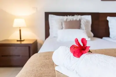 a white bed with a red flower on top of it at Quinta Barracuda in Albufeira