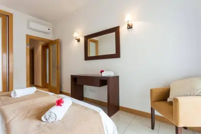 a room with two beds and a chair and a mirror at Quinta Barracuda in Albufeira