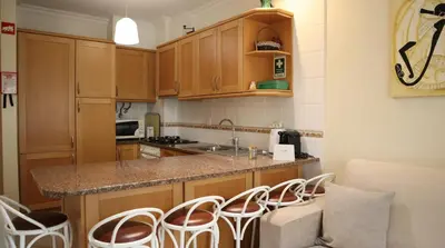 a kitchen with wooden cabinets and a counter with stools at Casablanca By Albufeira Rental in Albufeira