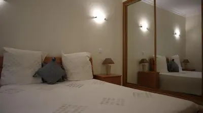 a bedroom with a white bed with a large mirror at Casablanca By Albufeira Rental in Albufeira
