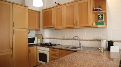a kitchen with wooden cabinets and a sink at Casablanca By Albufeira Rental in Albufeira