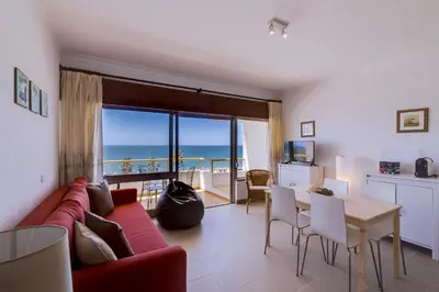 a living room with a red couch and a table with chairs at York - Sea view - Quarteira in Quarteira