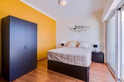 a bedroom with a bed and an orange wall at Sky - wonderful view to the beach - Quarteira in Quarteira