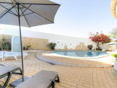 a patio with an umbrella and a swimming pool at Casa Vilamoura in Vilamoura