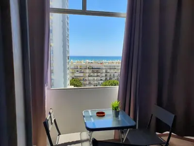 a table and chairs in a room with a window at Apartamento de Quarteira in Quarteira