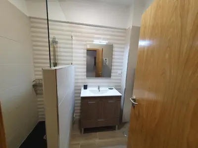 a bathroom with a sink and a mirror and a door at Apartamento de Quarteira in Quarteira