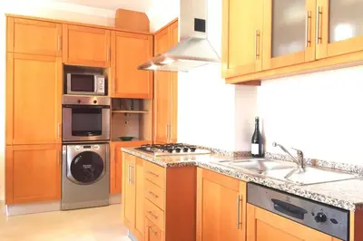 a kitchen with wooden cabinets and a stove top oven at Edificio Sao Joao das areias Strip l OURA in Albufeira