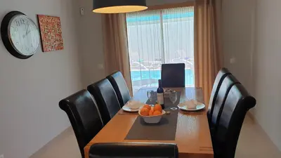 a dining room table with a bowl of oranges and a clock at Luxury Villa Corcovada Nicole with privat heated pool in Albufeira