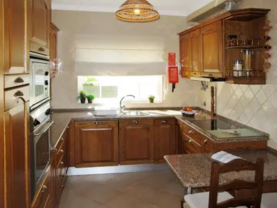 a kitchen with wooden cabinets and a sink and a window at Holiday Home Vila Sol by Interhome in Cabeço de Câmara