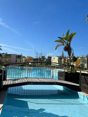 a bridge over a swimming pool with a palm tree at Colorful Cozy Apartment view in Albufeira