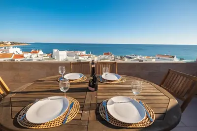 a table with plates and wine glasses on a balcony at #017 T2 Rossio by Home Holidays in Albufeira