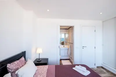 a white bedroom with a bed and a bathroom at #017 T2 Rossio by Home Holidays in Albufeira