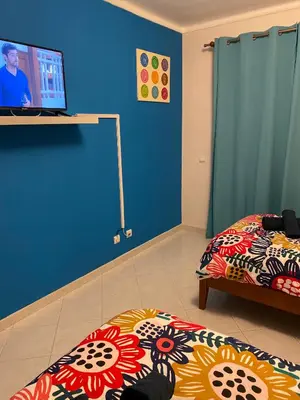 a room with two beds and a television on a wall at OCEAN VIEW Quartos in Faro