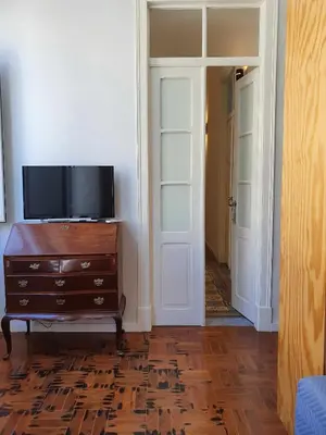 a room with a tv and a dresser and a door at Baron Faro - Guest House in Faro