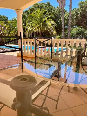a glass table in front of a pool with palm trees at Magellan House in Vilamoura