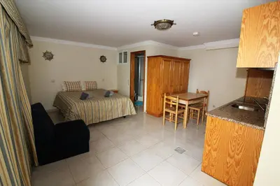 a bedroom with a bed and a table and a kitchen at Waves Studio - Albufeira in Albufeira