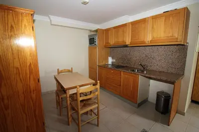 a kitchen with wooden cabinets and a table and a sink at Waves Studio - Albufeira in Albufeira