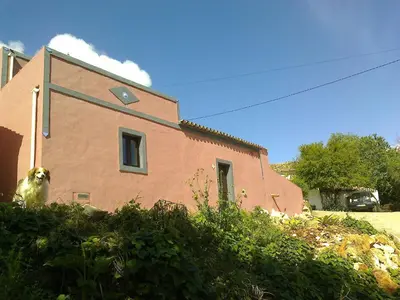 a dog is sitting in front of a house at Casa Do Forno - Quinta Amoreira in Faro