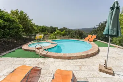 a swimming pool with chairs and an umbrella at Casa Do Forno - Quinta Amoreira in Faro
