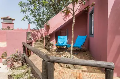 two blue chairs sitting on the porch of a pink house at Casa Adega - Quinta Amoreira in Faro