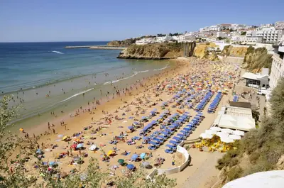 a beach with a lot of people and the ocean at Albufeira 1 bedroom apartment 5 min from Falesia beach and close to center J in Albufeira