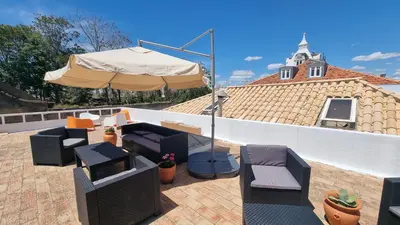 a patio with an umbrella and couches and a table and chairs at Happen!ng in Faro