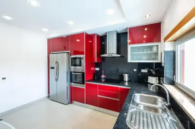 a kitchen with red cabinets and a stainless steel refrigerator at Villa Orada in Albufeira