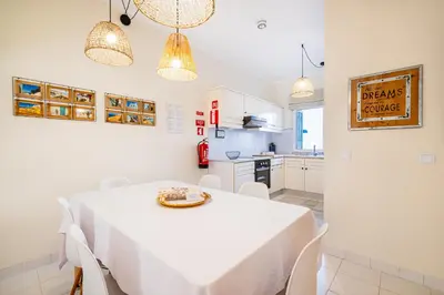a dining room with a white table and white chairs at All Dreams Apartment - Urbanização Windmill in Albufeira