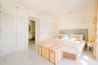 a white bedroom with a large bed and a bathroom at All Dreams Apartment - Urbanização Windmill in Albufeira