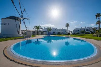a large blue swimming pool next to a windmill at All Dreams Apartment - Urbanização Windmill in Albufeira
