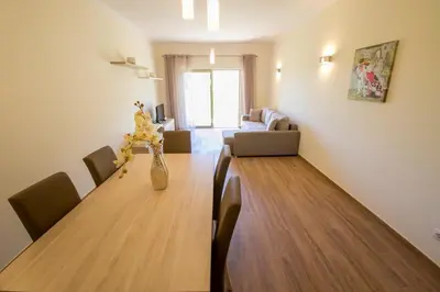 a dining room with a table and a living room at Marina Garden Apartment in Albufeira