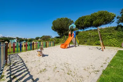 a playground with a slide in the sand at Marina Garden Apartment in Albufeira