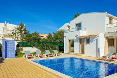a villa with a swimming pool in front of a house at Villa Machado in Albufeira